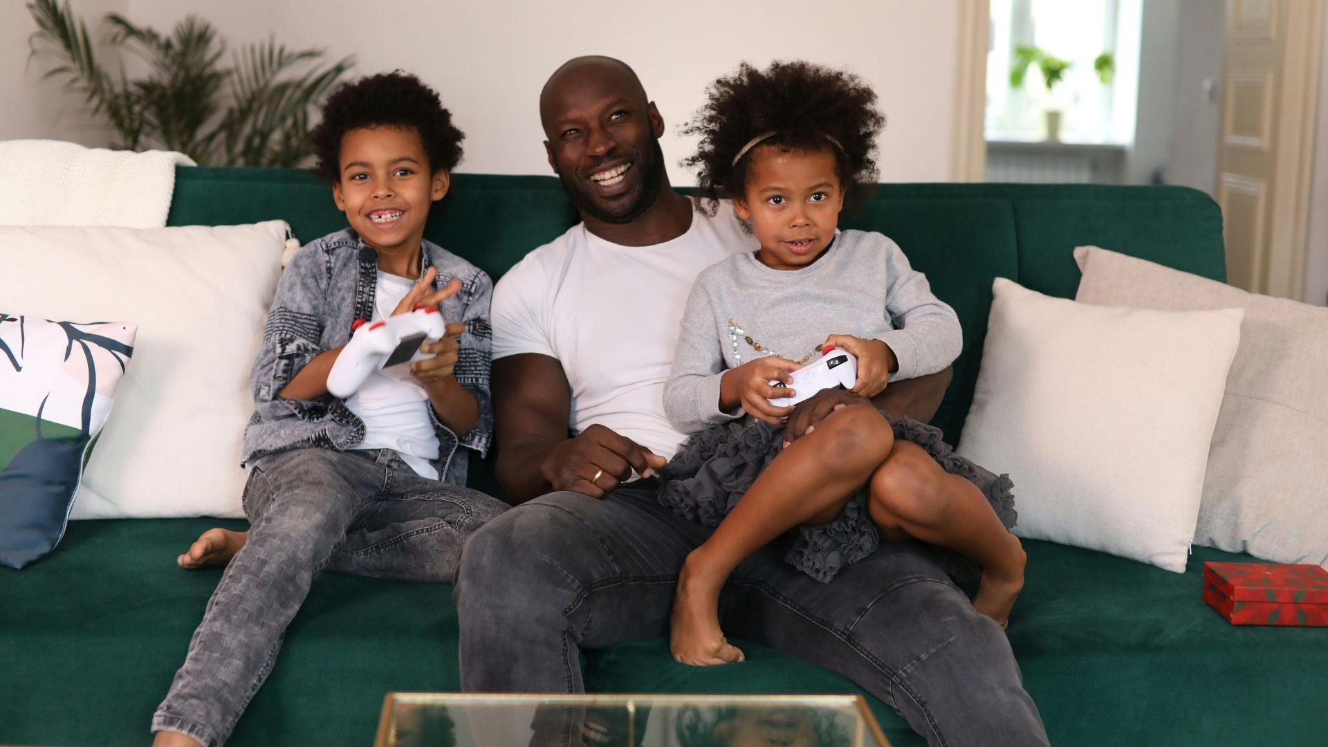 Happy dad and children playing video games together on the sofa