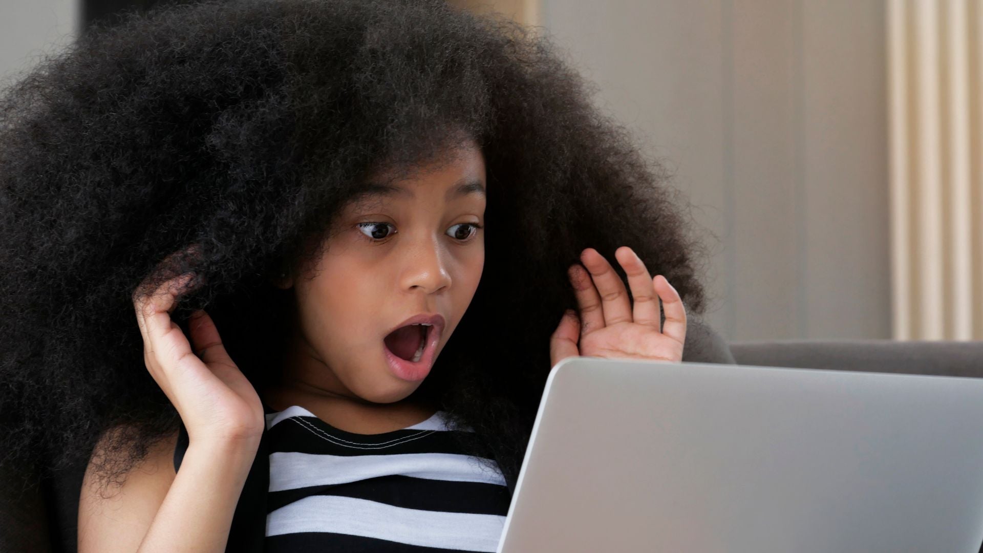 Girl shocked looking at her computer as she was scammed online
