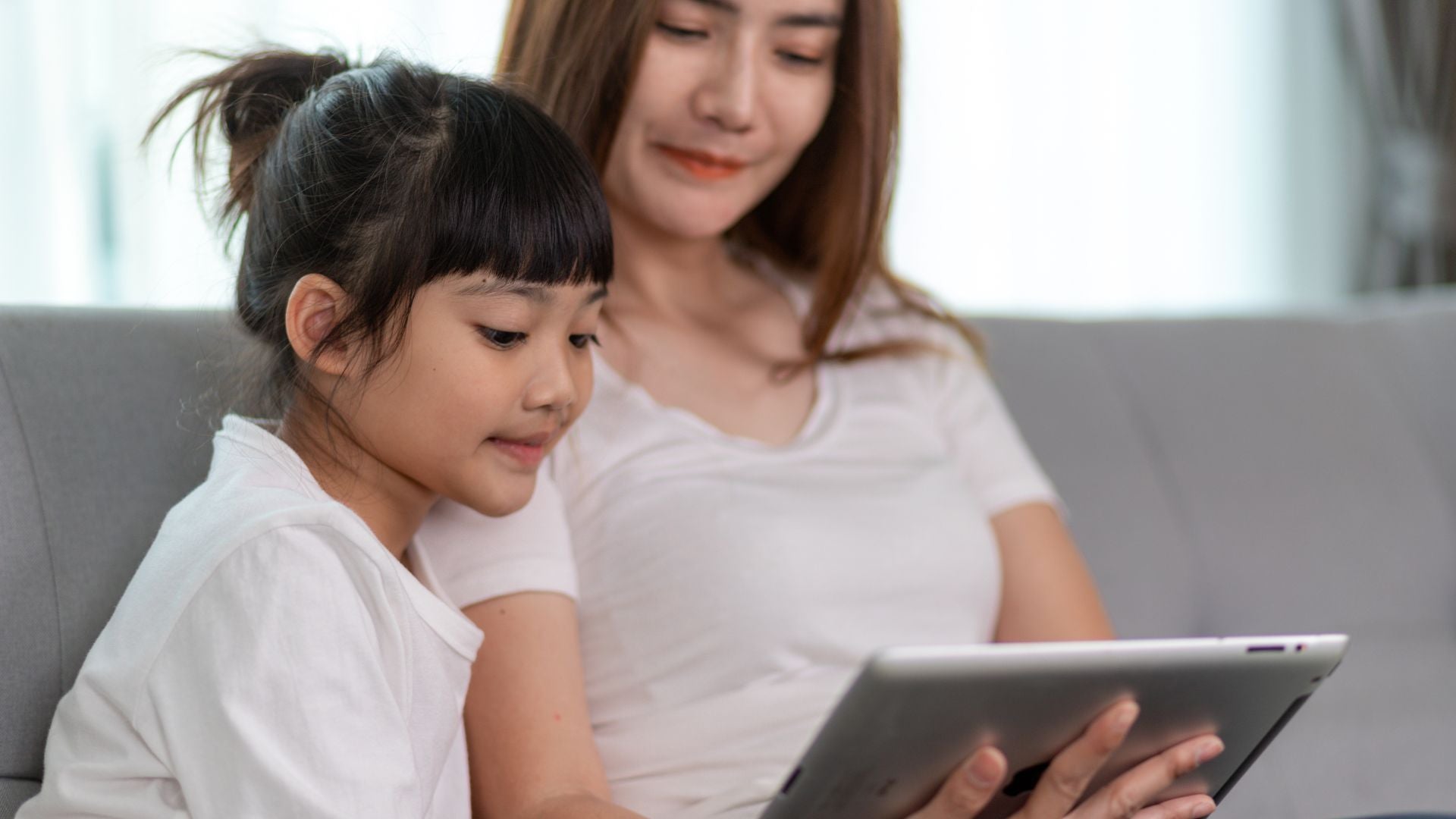 Mom teaching digital literacy to daughter, explaining what is safe and what isn't online